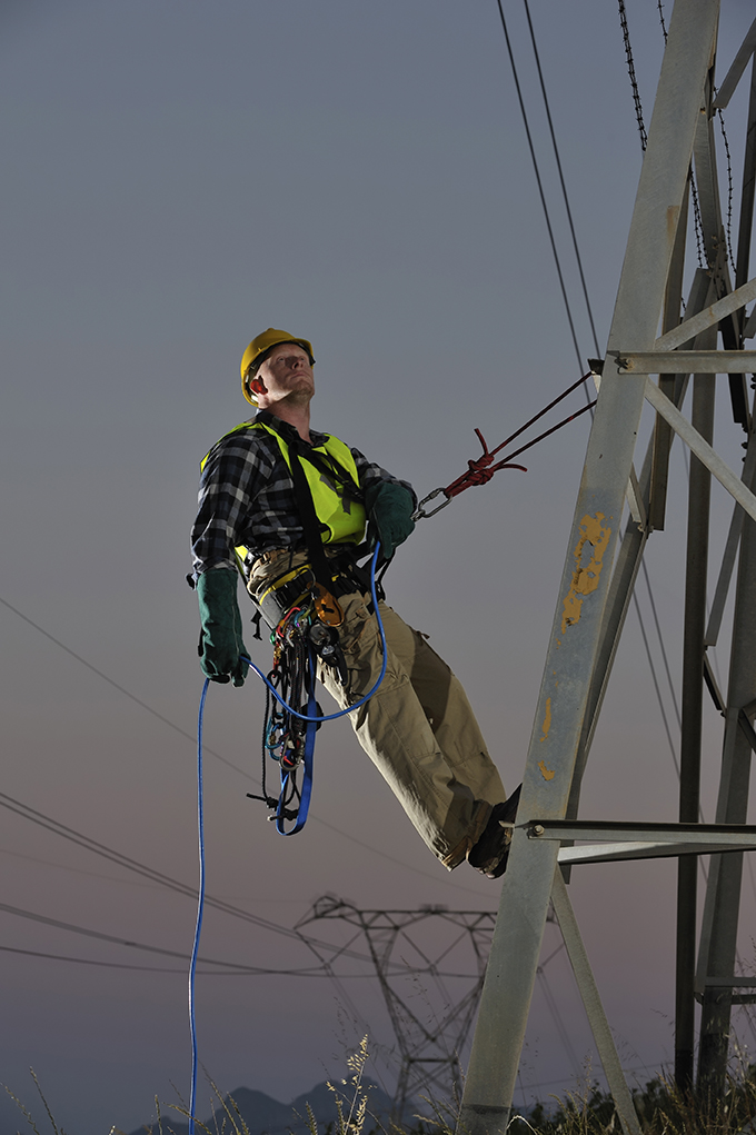 Power utility worker abseiling from pylons